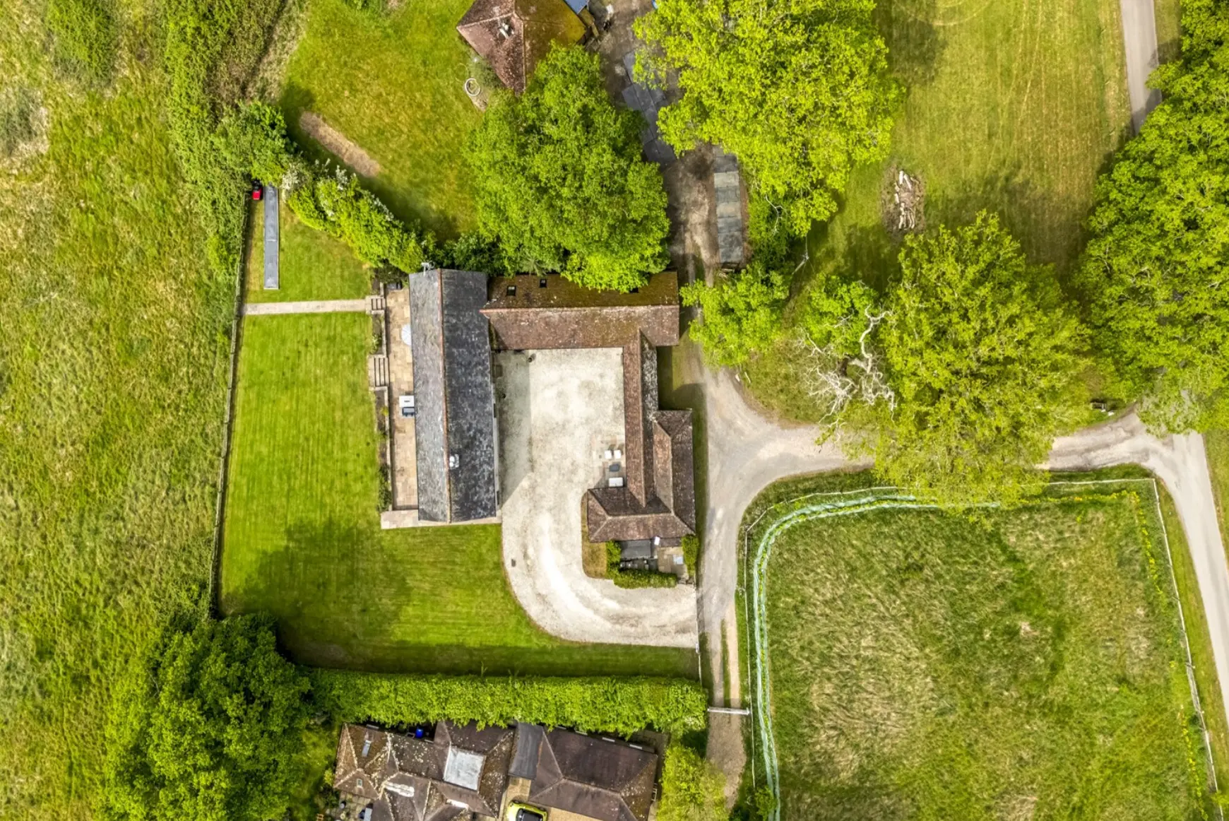 Aerial view looking straight down on the barn roofs, gravel courtyard, lawns and hedged fields